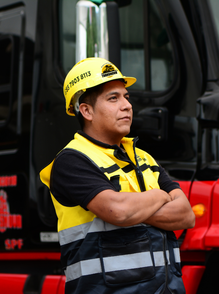 Operador de transporte de carga pesada en uniforme, listo para asegurar la entrega segura de maquinaria y equipos industriales.